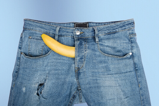 Eine Banane schaut aus einer Hose als Symbol für einen Penis
